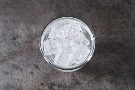 Refreshing soda water with ice cubes in glass on grey table, top viewの写真素材