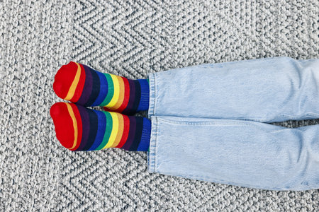 Man wearing socks in colors of LGBT flag on floor indoors, top view