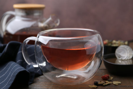Delicious herbal tea with honey and dry leaves on wooden table, closeupの写真素材