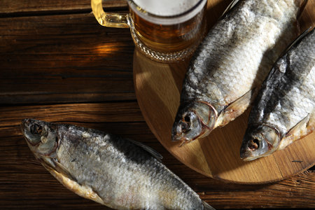 Dried roach fish and glass of beer on wooden table, flat layの写真素材