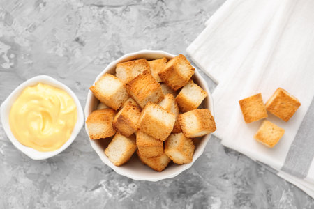 Tasty crispy croutons and sauce on grey textured table, flat layの写真素材