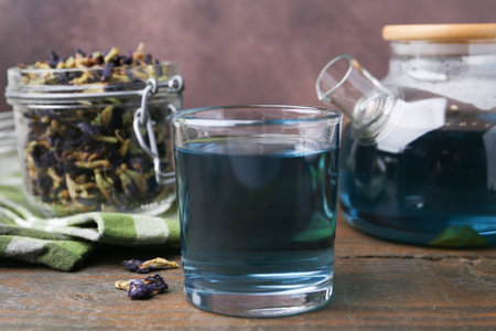 Delicious butterfly pea flower tea on wooden table against brown backgroundの写真素材