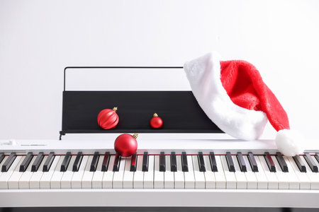 Christmas ornaments and Santa hat on synthesizer against white background, closeupの写真素材