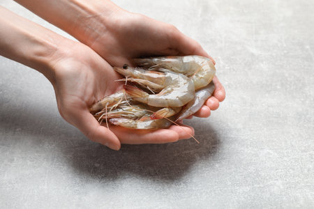 Woman with fresh raw shrimps at grey table, closeup.の写真素材