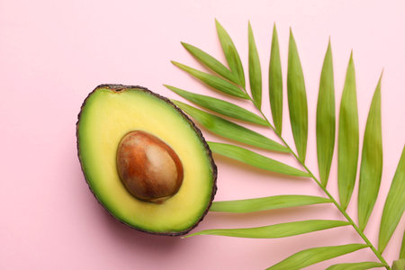 One cut ripe avocado and leaf on pink background, closeup
