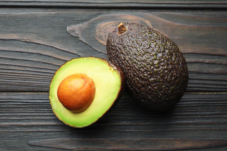 Whole and cut avocados on dark wooden table, flat layの写真素材