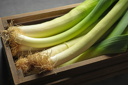 Fresh raw leeks in wooden crate on grey table, closeupの写真素材