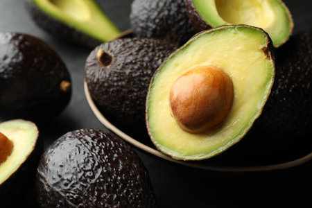 Whole and cut avocados on dark table, closeupの写真素材