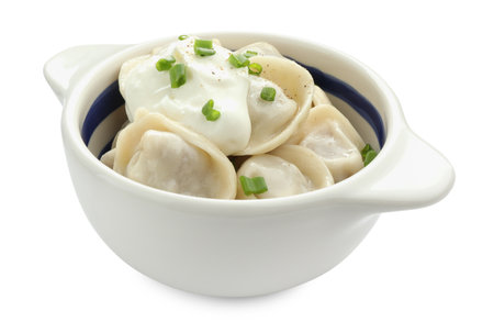 Delicious dumplings (pelmeni) with green onion and sour cream in bowl isolated on whiteの写真素材