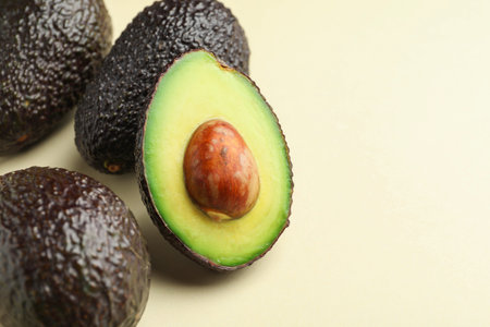 Fresh ripe avocados on beige background, closeup. Space for text