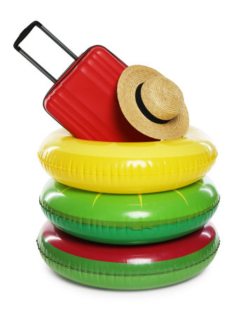 Bright inflatable rings, suitcase and straw hat on white background