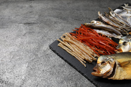 Many different dried fish snacks on grey table, closeup. Space for textの写真素材