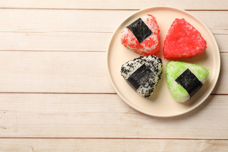 Tasty tobiko onigiri (Japanese rice balls) on white wooden table, top view. Space for text