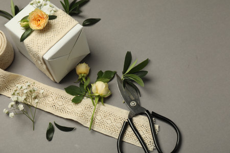 Florist. Box, flowers, leaves and scissors on grey background, above view. Space for textの写真素材