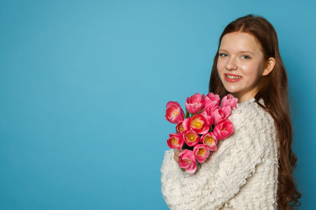 Beautiful teenage girl with bouquet of tulips on light blue background, space for textの写真素材