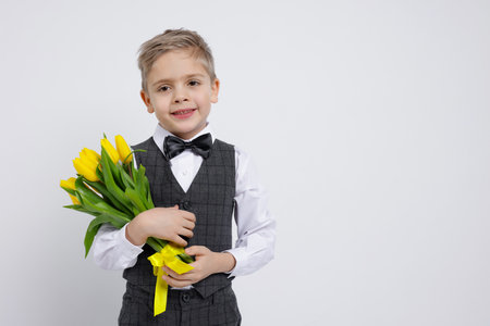 Cute little boy with bouquet of tulips on white background. Space for textの写真素材