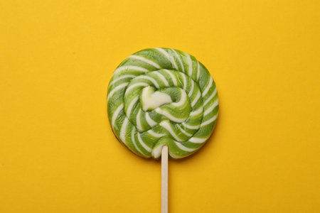 Tasty striped lollipop on yellow background, top viewの写真素材