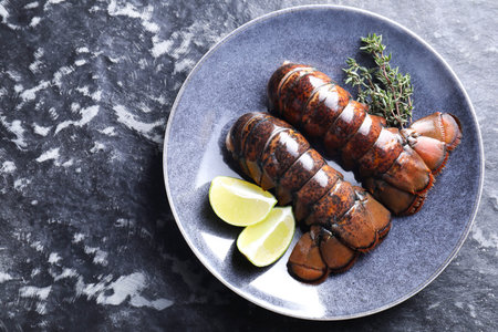 Raw lobster tails, lime and thyme on dark table, top view. Space for textの写真素材