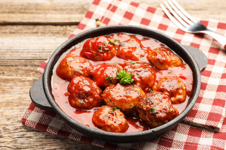 Delicious meatballs with tomato sauce in baking dish on wooden table, closeupの写真素材