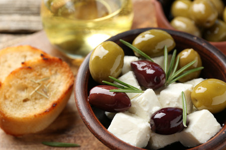 Marinated olives with feta cheese, bread pieces, oil and rosemary on wooden table, closeupの写真素材