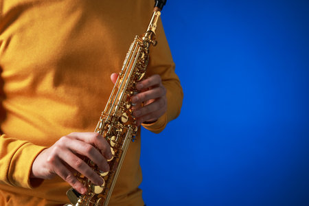 Professional musician with soprano saxophone on blue background, closeup. Space for textの写真素材