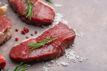 Pieces of raw beef and spices on brown textured table, closeup. Space for textの写真素材
