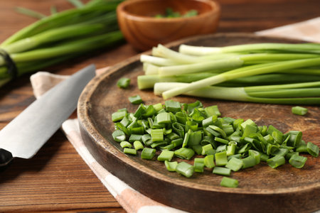 Fresh green onions and knife on wooden table, closeupの写真素材