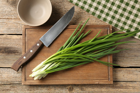 Fresh green onions and knife on wooden table, top viewの写真素材