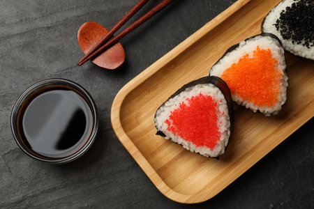 Tasty tobiko onigiri (Japanese rice balls) served on black table, flat layの写真素材