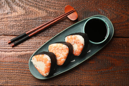 Tasty onigiri (Japanese rice balls) with shrimps served on wooden table, flat layの写真素材