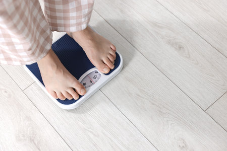 Woman on scales indoors, closeup with space for text. Weight loss