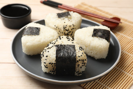 Rice balls (onigiri), soy sauce and chopsticks on wooden table, closeup. Traditional Japanese dishの写真素材
