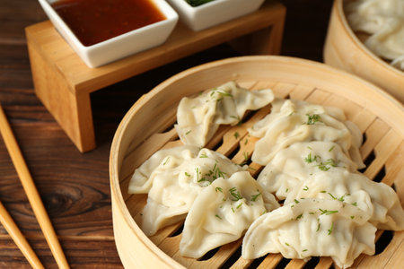Tasty boiled gyoza (dumplings) in bamboo steamers, sauce and chopsticks on wooden table, closeupの写真素材