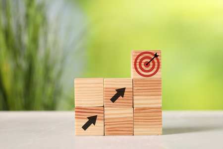 Targeting. Stacked cubes with arrows pointing at one with bullseye on top against blurred green backgroundの写真素材