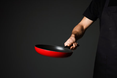 Chef holding frying pan on black background, closeupの写真素材
