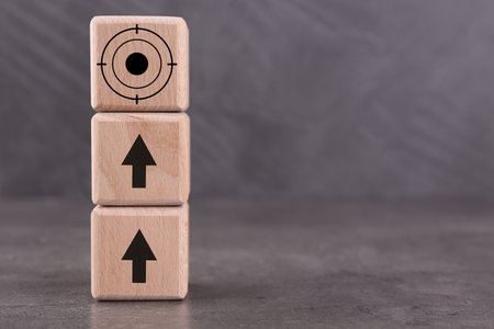 Targeting. Stacked cubes with arrows pointing at one with bullseye on top on grey tableの写真素材