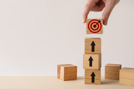 Targeting. Woman putting cube with bullseye on top of other ones with arrows on wooden table,...