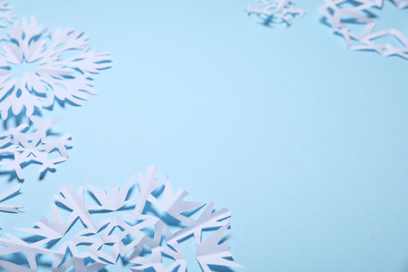 Beautiful paper snowflakes on light blue background, closeup. Space for textの写真素材