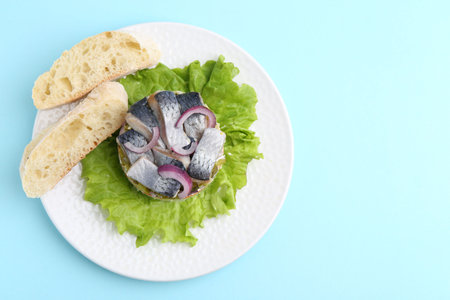 Delicious salad with herring, vegetables and bread on light blue background, top view. Space for textの写真素材