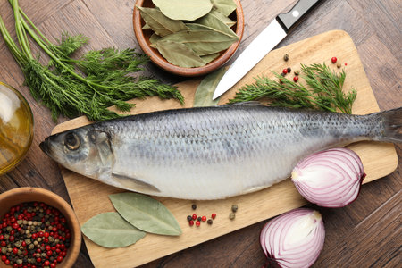 Salted herring, spices and knife on wooden table, flat layの写真素材