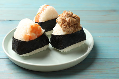 Tasty onigiri (Japanese rice balls) served on blue wooden table, closeupの写真素材