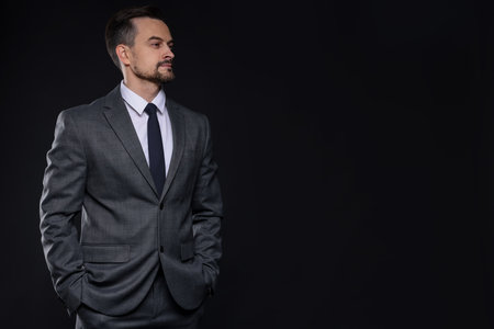 Confident man in classic suit on black background. Space for textの写真素材