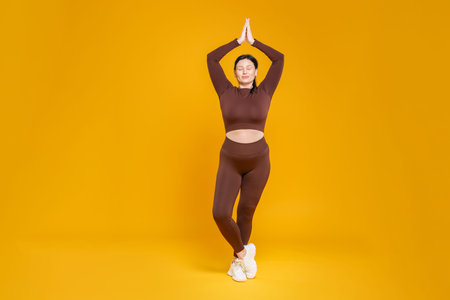 Plus size woman in gym clothes on orange background