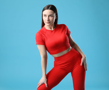 Woman in sportswear posing on light blue backgroundの写真素材