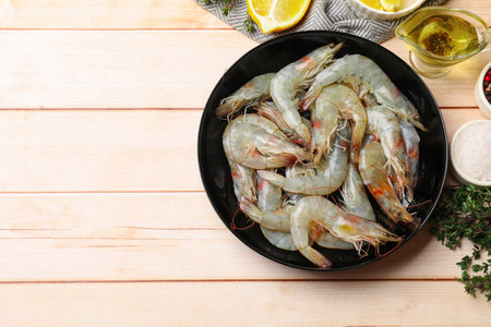 Fresh raw shrimps and spices on wooden table, flat lay. Space for textの写真素材