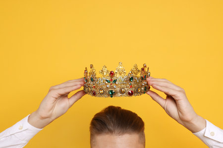 Man wearing luxury crown on orange background, closeupの写真素材