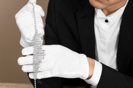 Appraiser in gloves with luxury necklace on beige background, closeupの写真素材