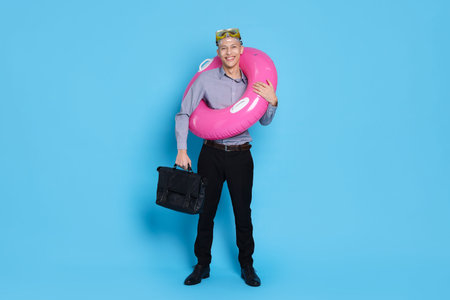 Businessman with inflatable ring, briefcase and diving mask on light blue backgroundの写真素材