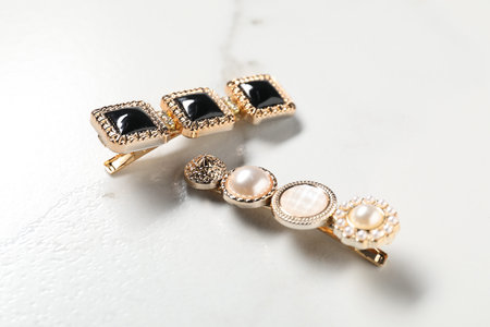 Beautiful hair clips on white marble table, closeup