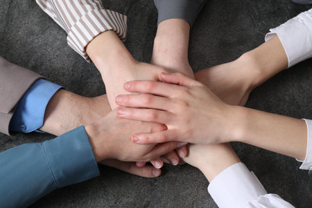 Business concept. Group of people stacking hands at gray textured table, above viewの写真素材